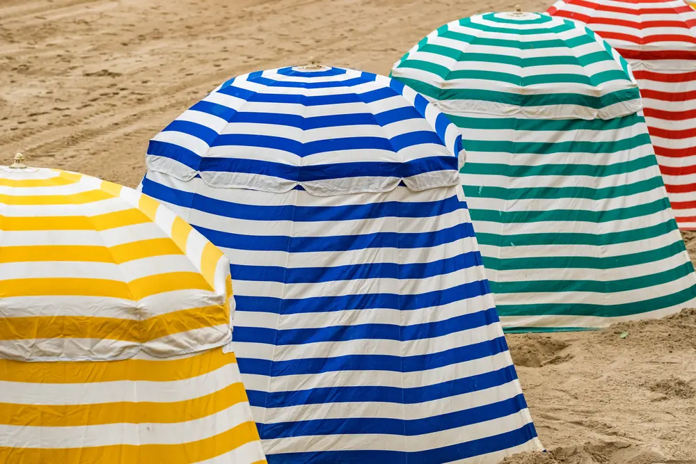 Yellow, blue, green and red striped beach tents on the sand